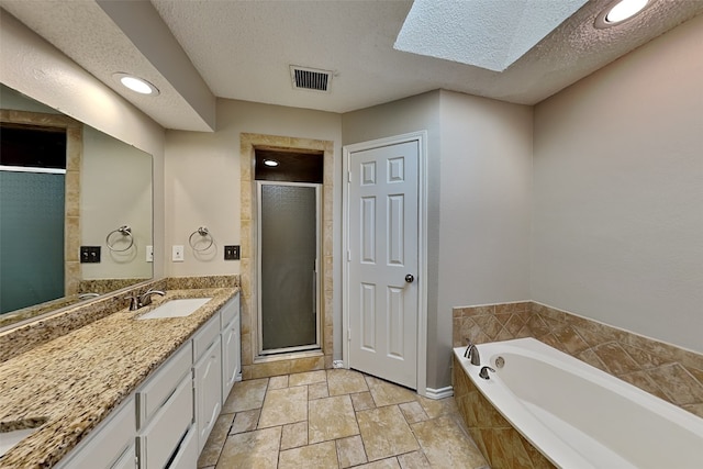 bathroom with vanity, a skylight, a textured ceiling, and plus walk in shower