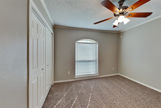 unfurnished bedroom with dark carpet, a closet, ceiling fan, and ornamental molding