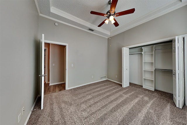 unfurnished bedroom with ceiling fan, carpet, a tray ceiling, and crown molding