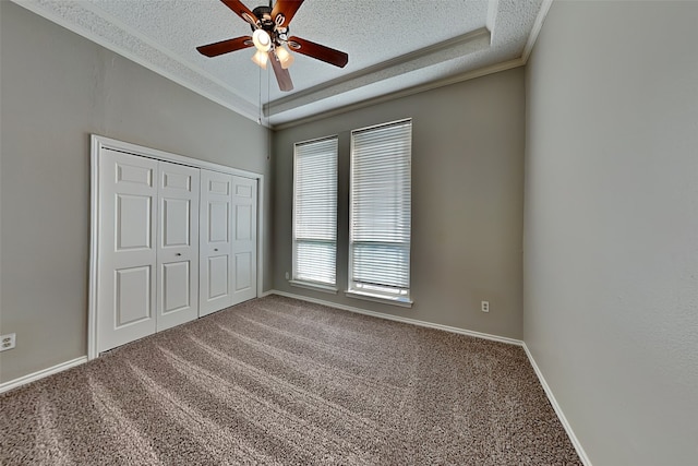 unfurnished bedroom with ceiling fan, carpet flooring, a textured ceiling, ornamental molding, and a closet