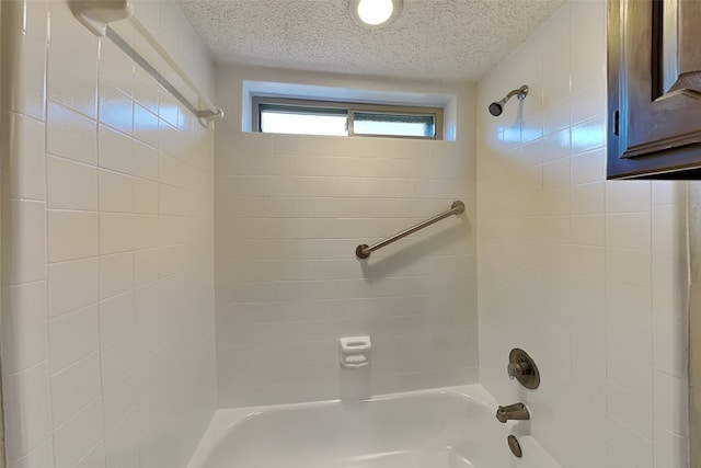 bathroom with tiled shower / bath combo and a textured ceiling