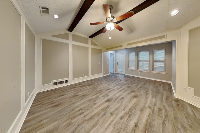 unfurnished room with light wood-type flooring, a textured ceiling, vaulted ceiling with beams, and ceiling fan