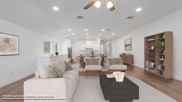 living area featuring baseboards, a ceiling fan, light wood-style flooring, and visible vents
