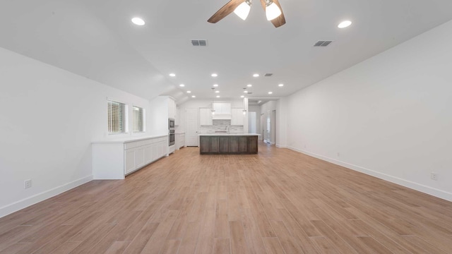 unfurnished living room with visible vents, light wood-style floors, ceiling fan, and baseboards