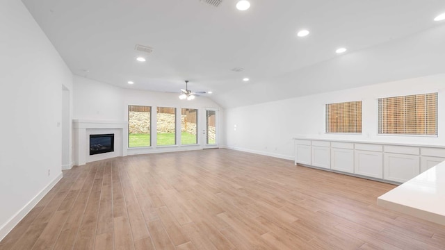 unfurnished living room with a ceiling fan, visible vents, lofted ceiling, and light wood-style floors