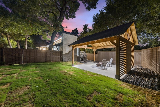 yard at dusk featuring a gazebo, a patio area, and a fire pit