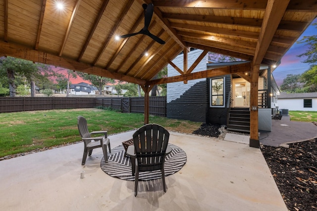 patio terrace at dusk with ceiling fan, a gazebo, and a yard