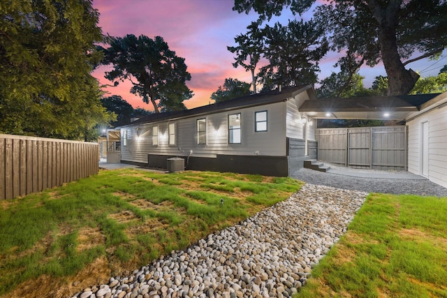 view of front of home with a lawn and central AC