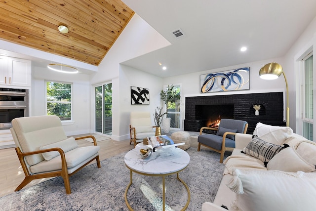 living room featuring vaulted ceiling, wooden ceiling, light wood-type flooring, and a fireplace