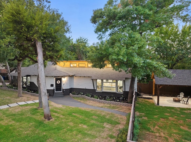 view of front of home featuring a front yard, a patio area, and a fire pit