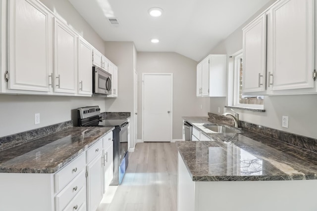 kitchen with white cabinets, appliances with stainless steel finishes, sink, and dark stone countertops