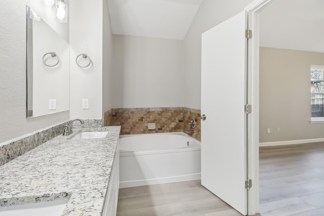 bathroom with a bath, vaulted ceiling, and vanity