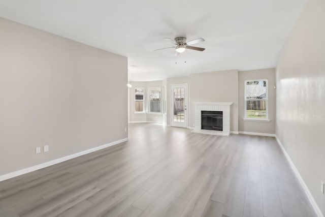 unfurnished living room with ceiling fan, a fireplace, and light hardwood / wood-style floors