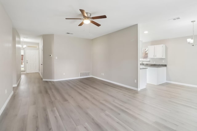 unfurnished living room with light hardwood / wood-style floors and ceiling fan with notable chandelier