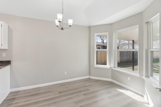 unfurnished dining area featuring plenty of natural light, light hardwood / wood-style flooring, and a chandelier