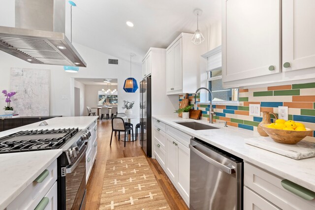 10414 Robindale Dr, Dallas, TX 75238 - kitchen featuring a sink, white cabinetry, vaulted ceiling, wall chimney range hood, and appliances with stainless steel finishes