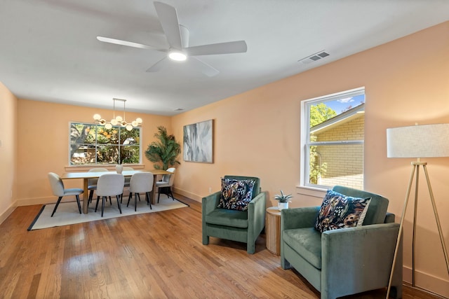 dining room with ceiling fan with notable chandelier and light hardwood / wood-style flooring