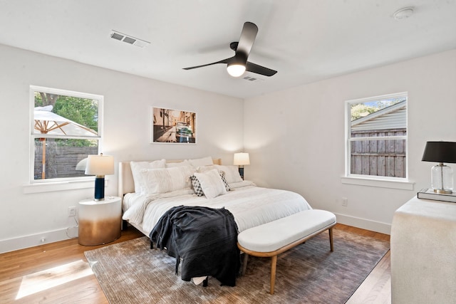 bedroom featuring ceiling fan, light hardwood / wood-style floors, and multiple windows