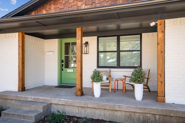 entrance to property with a porch and brick siding