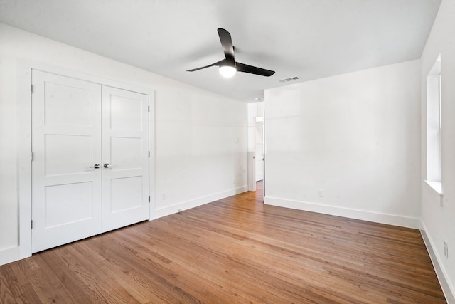 unfurnished bedroom with ceiling fan, a closet, and wood-type flooring