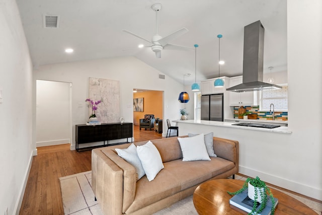 living room with ceiling fan, light hardwood / wood-style floors, and lofted ceiling