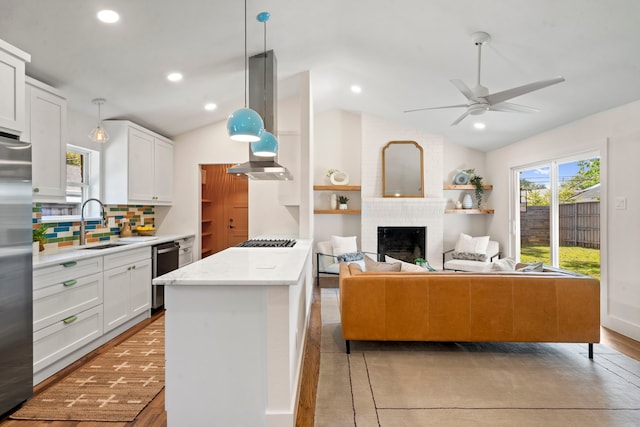 10414 Robindale Dr, Dallas, TX 75238 - kitchen featuring stainless steel appliances, lofted ceiling, backsplash, a brick fireplace, and white cabinets