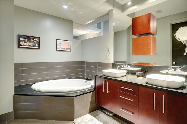 bathroom featuring vanity, tile patterned floors, and a relaxing tiled tub