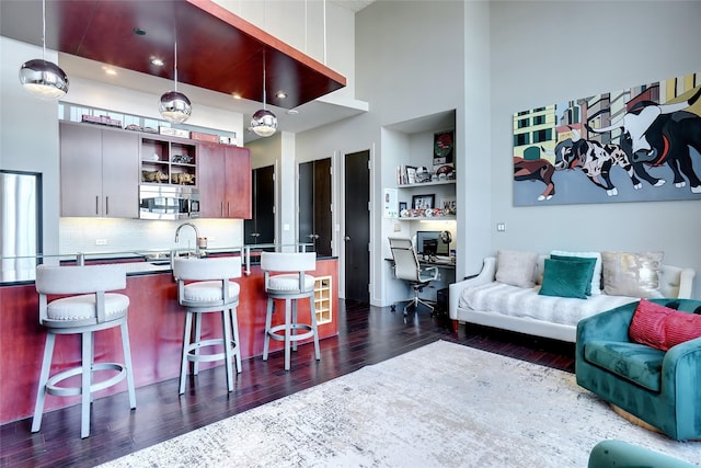 kitchen featuring decorative light fixtures, dark hardwood / wood-style flooring, tasteful backsplash, a kitchen breakfast bar, and sink