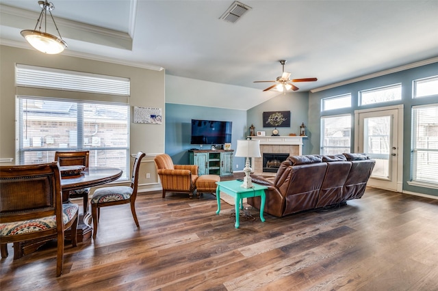 living room featuring ceiling fan, dark wood-type flooring, a tile fireplace, and plenty of natural light