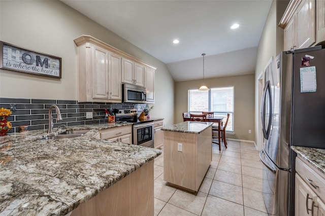 kitchen featuring stainless steel appliances, light stone countertops, vaulted ceiling, a kitchen island, and sink