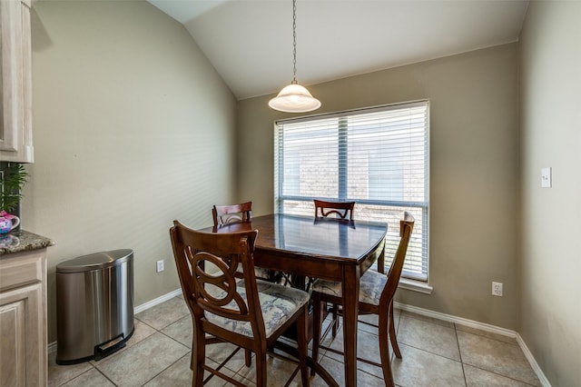 tiled dining room with a healthy amount of sunlight and vaulted ceiling