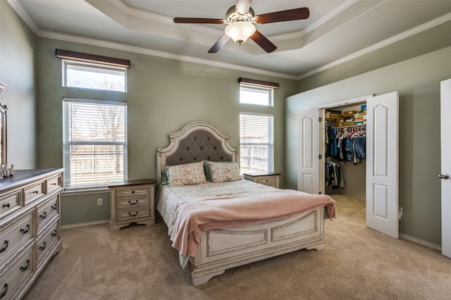 bedroom featuring ceiling fan, a raised ceiling, a spacious closet, light carpet, and a closet