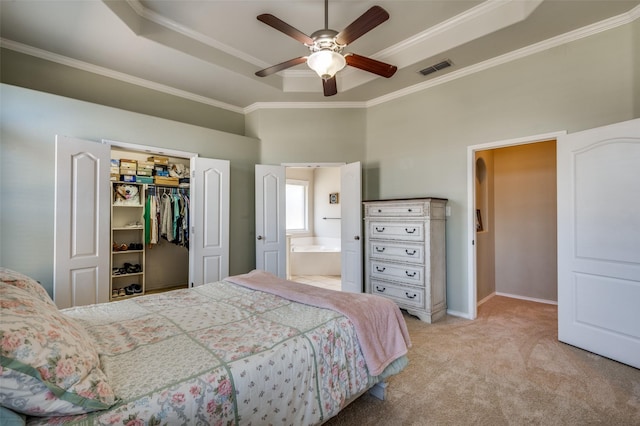 bedroom featuring ensuite bath, light carpet, a closet, ceiling fan, and a tray ceiling