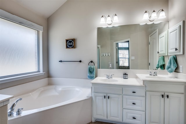 bathroom featuring lofted ceiling, vanity, a tub, and a wealth of natural light