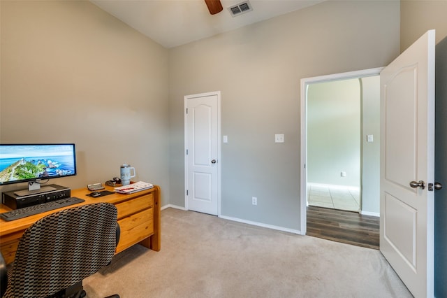 office area with ceiling fan, light colored carpet, and a towering ceiling