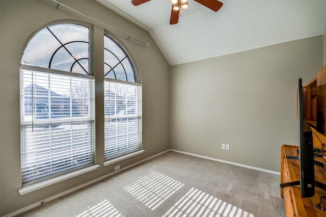 carpeted spare room with ceiling fan, a wealth of natural light, and lofted ceiling