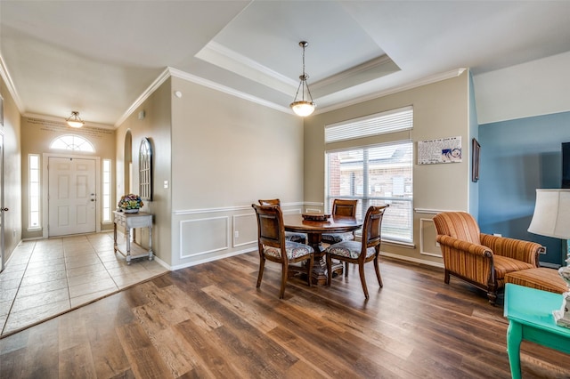 dining space with hardwood / wood-style floors, a tray ceiling, and ornamental molding