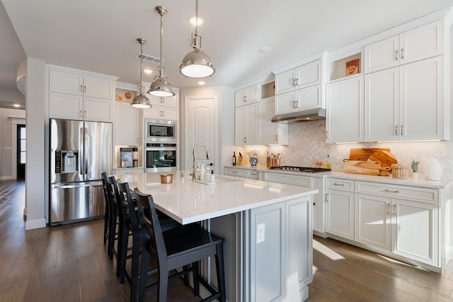 kitchen featuring stainless steel appliances, white cabinetry, and a center island with sink