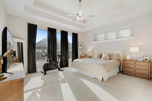 carpeted bedroom featuring ceiling fan and a tray ceiling