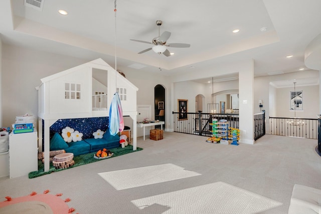 playroom with a tray ceiling, carpet floors, and ceiling fan with notable chandelier