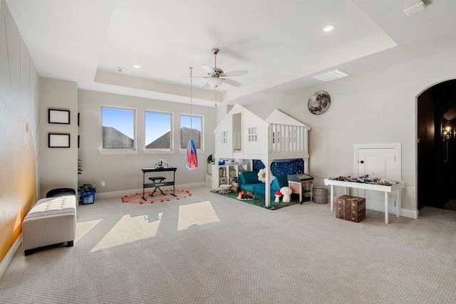 rec room with light carpet, a tray ceiling, and ceiling fan