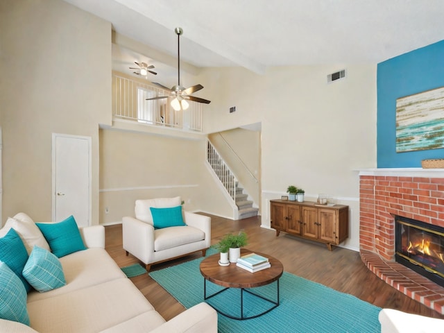 living room with ceiling fan, vaulted ceiling with beams, a fireplace, and hardwood / wood-style flooring