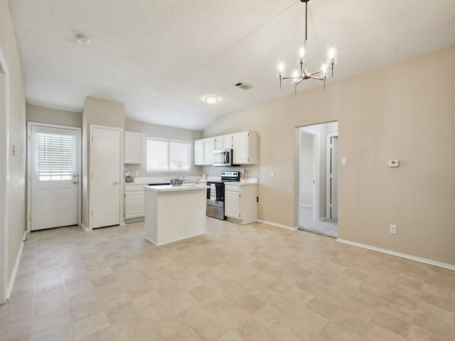 kitchen with an inviting chandelier, appliances with stainless steel finishes, decorative light fixtures, a kitchen island, and white cabinets