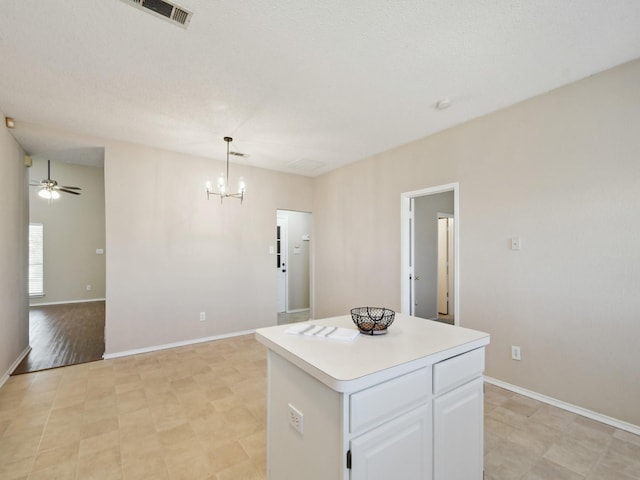 kitchen featuring decorative light fixtures, ceiling fan with notable chandelier, white cabinetry, and a center island