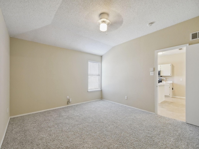 carpeted spare room featuring lofted ceiling, ceiling fan, and a textured ceiling