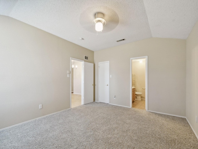 unfurnished bedroom featuring ceiling fan, lofted ceiling, a textured ceiling, connected bathroom, and light carpet