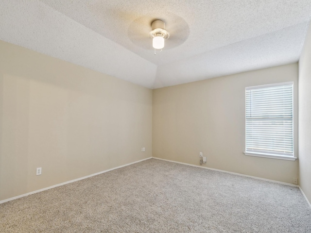 carpeted empty room with ceiling fan, a textured ceiling, and vaulted ceiling