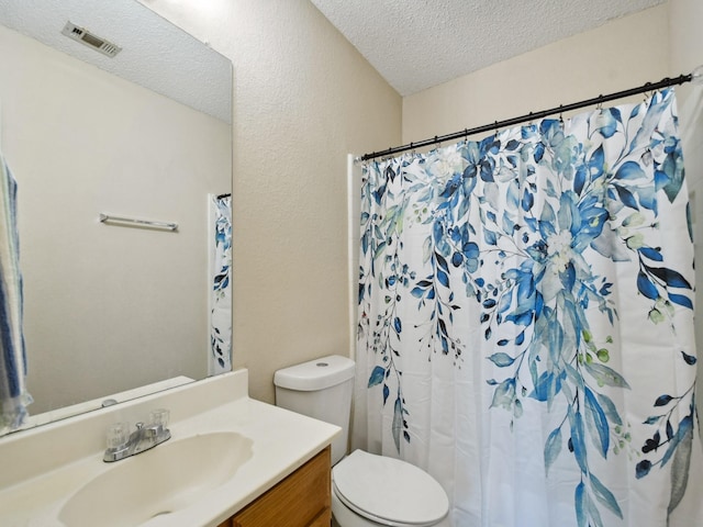 bathroom featuring a textured ceiling, toilet, and vanity