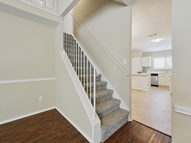 staircase with a textured ceiling and hardwood / wood-style floors