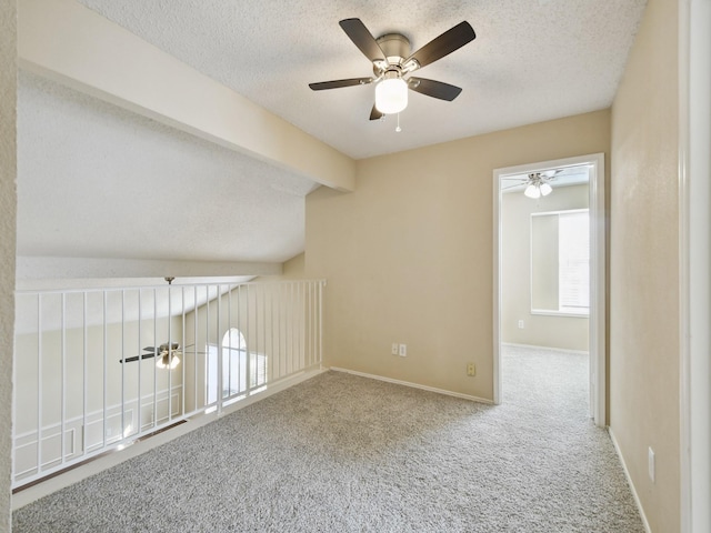 unfurnished room featuring carpet floors, a textured ceiling, lofted ceiling with beams, and ceiling fan